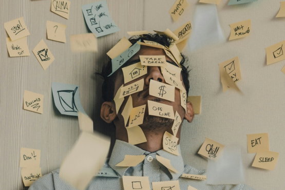 man covered in sticky notes at office desk